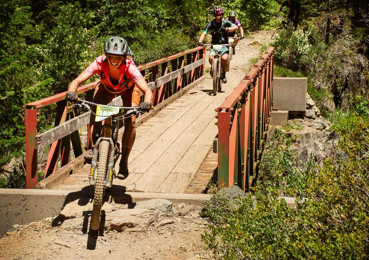 mountain bike racer crossing Pauly Creek bridge