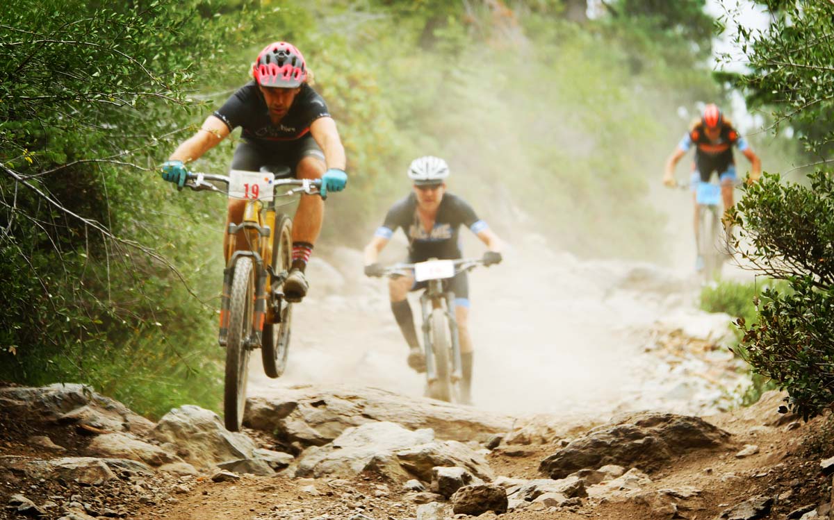 mountain bike racers jumping over rocks